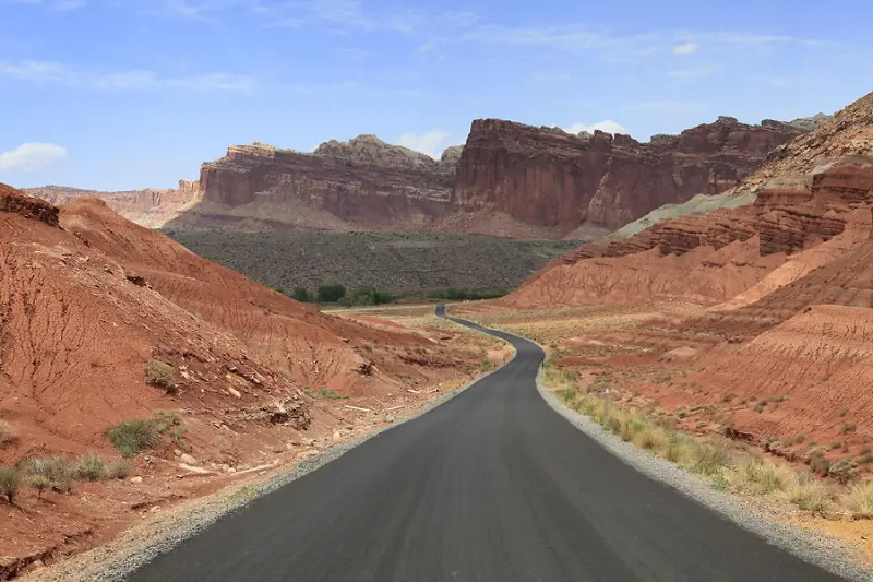 Capitol Reef Park의 붉은 절벽 사이로 곧게 뻗은 도로